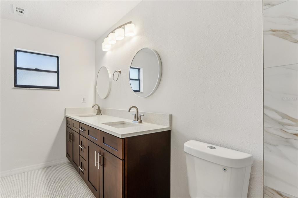 10237 Carrin Road Spring Hill, FL 34608 - Photo 17 of 39 a bathroom with a toilet a sink and mirror
