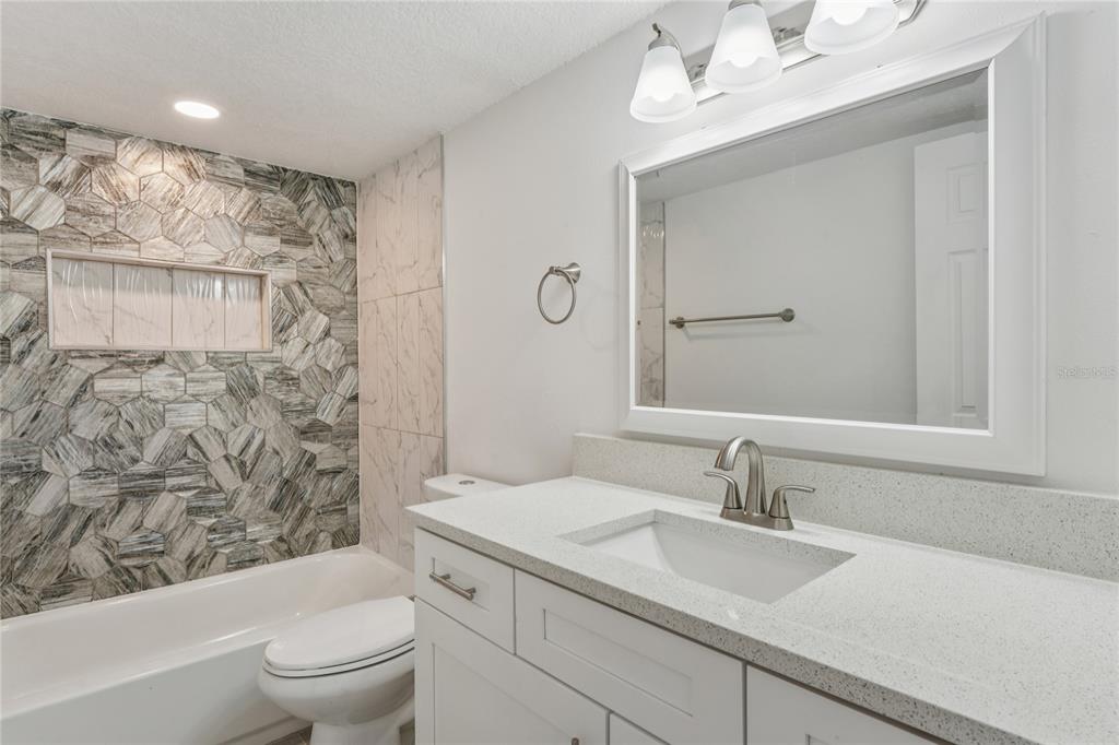 10237 Carrin Road Spring Hill, FL 34608 - Photo 22 of 39 a bathroom with a granite countertop sink a toilet and shower