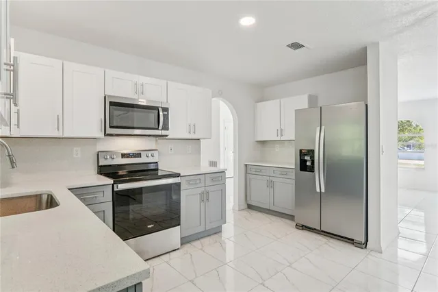 a kitchen with stainless steel appliances granite countertop a refrigerator a stove top oven a sink and dishwasher