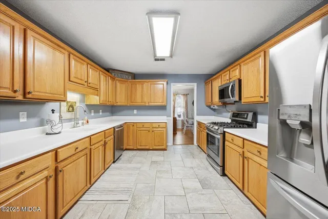a large kitchen with stainless steel appliances granite countertop a stove a sink dishwasher and a microwave oven with white cabinets