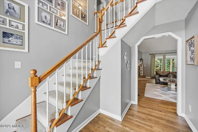 a view of staircase with lots of frames on wall and a dining table