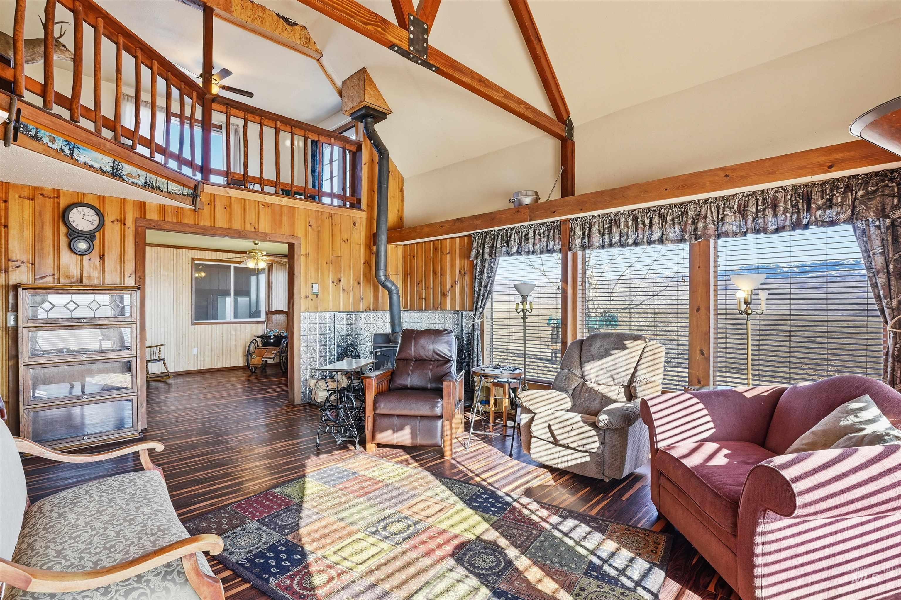 1252 Mesa Mesa, ID 83643 - Photo 6 of 50 Living room featuring ceiling fan, wood-type flooring, wooden walls, vaulted ceiling, and a wood stove