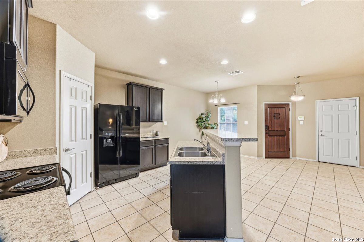 3831 Bacall Way Converse, TX 78109 - Photo 11 of 33 a kitchen with stainless steel appliances kitchen island granite countertop a refrigerator and a sink