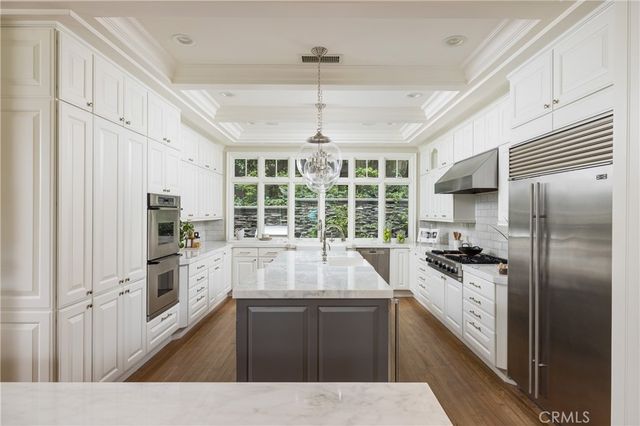a kitchen with a center island wooden floor and stainless steel appliances