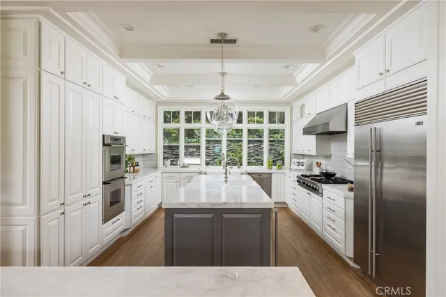 a kitchen with a center island wooden floor and stainless steel appliances