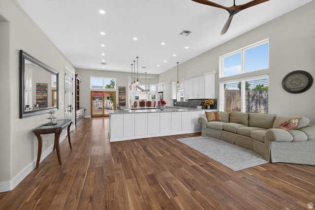 4297 Beeman Road Moab, UT 84532 - Photo 2 of 59 Spacious open-concept interior featuring wood-finish flooring throughout, a large kitchen island with a stone countertop, white shaker-style cabinetry, and high ceilings with recessed lighting