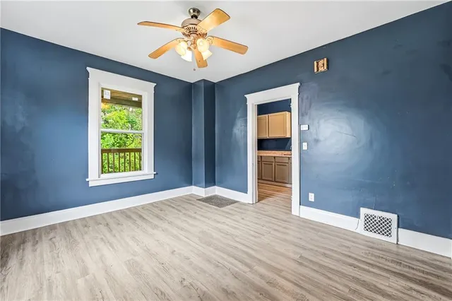 a view of an empty room with window and wooden floor