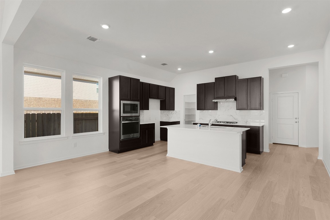 25621 Flora Bella Lane Elgin, TX 78621 - Photo 12 of 27 Kitchen featuring tasteful backsplash, stainless steel appliances, recessed lighting, dark brown cabinetry, and light wood-style floors