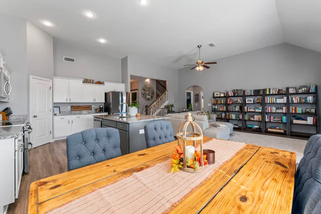 a room with stainless steel appliances kitchen island granite countertop a table chairs in it and a wooden floor