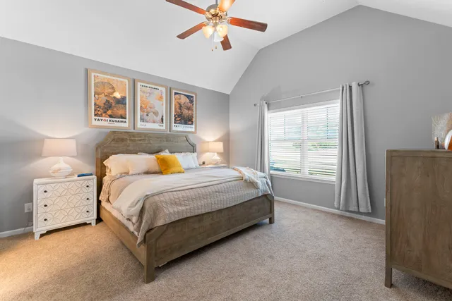 a spacious bedroom with a bed and a lamp on dresser