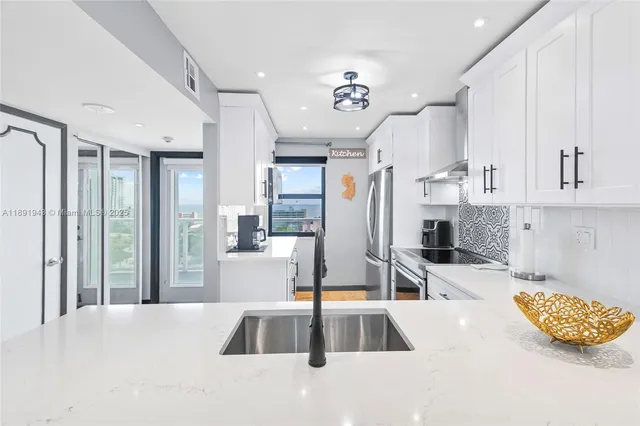 a kitchen with stainless steel appliances kitchen island granite countertop a refrigerator and a sink