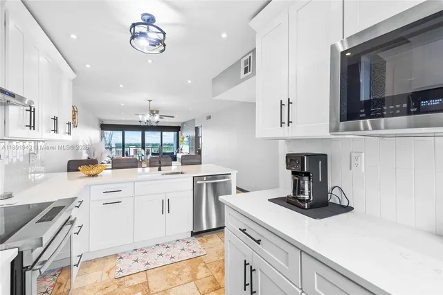 a kitchen with a sink dishwasher stove and white cabinets