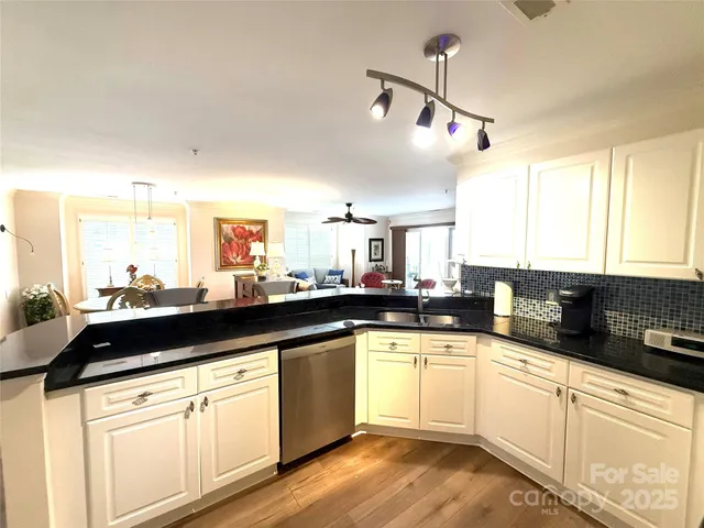 a kitchen with a sink dishwasher and white cabinets with wooden floor