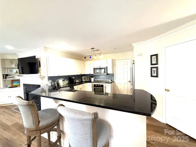 a kitchen with stainless steel appliances kitchen island granite countertop a table and chairs in it