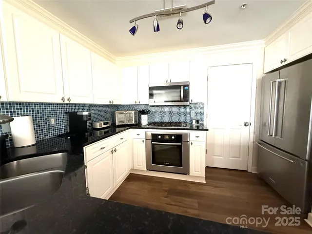 a kitchen with granite countertop a refrigerator stove top oven and sink
