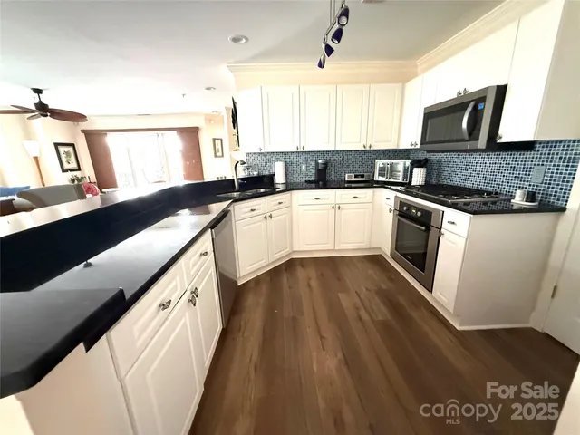 a kitchen with stainless steel appliances granite countertop a sink a stove top oven a counter space and cabinets