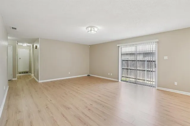 a view of an empty room with wooden floor and closet