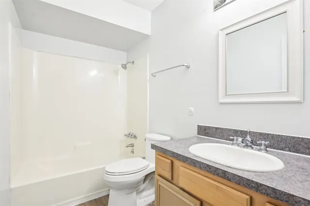 a bathroom with a granite countertop sink toilet and a mirror