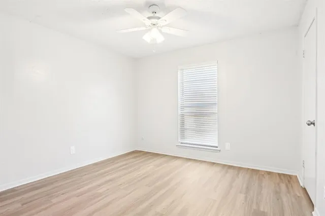 an empty room with a window and a ceiling fan