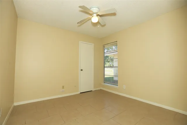 an empty room with closet and a ceiling fan