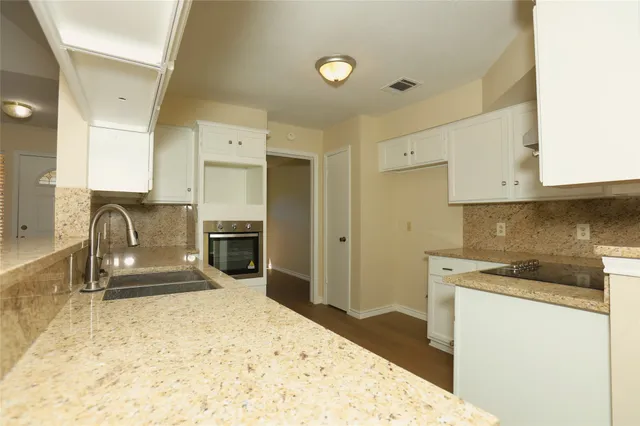a kitchen with granite countertop a refrigerator sink and cabinets