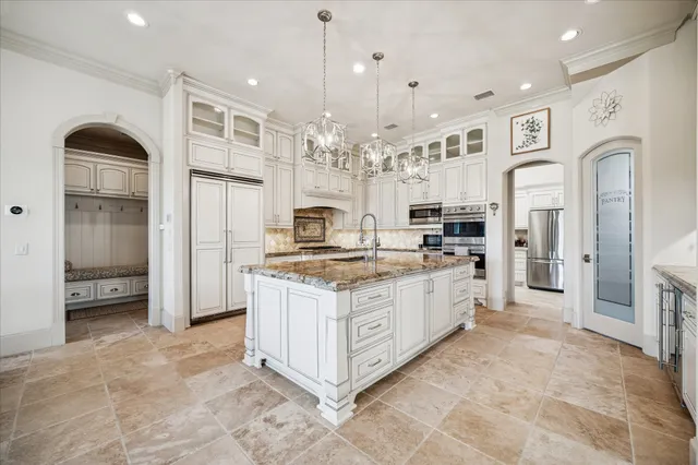a large white kitchen with granite countertop a sink stove and cabinets