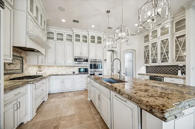 a kitchen with stainless steel appliances granite countertop a stove top oven a sink a counter top space and living room view