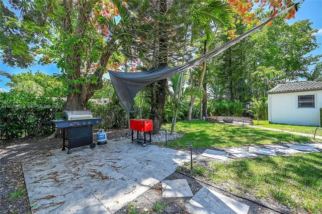 a view of a backyard with table and chairs plants and large trees