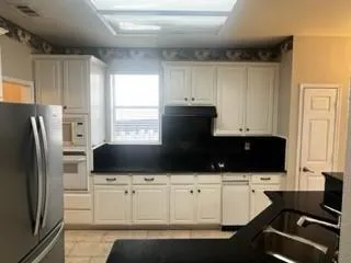 a kitchen with white cabinets and refrigerator