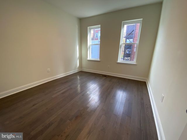a view of an empty room with wooden floor and closet