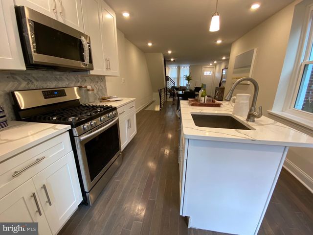 a kitchen with stainless steel appliances a stove a microwave a sink and a hard wood floors