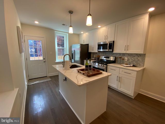 a kitchen that has a lot of cabinets a sink and wooden floor