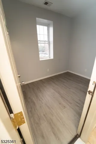 an empty room with wooden floor and mirror