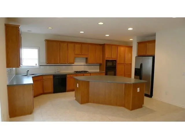 a kitchen with stainless steel appliances a refrigerator a sink a stove top oven a counter space and cabinets