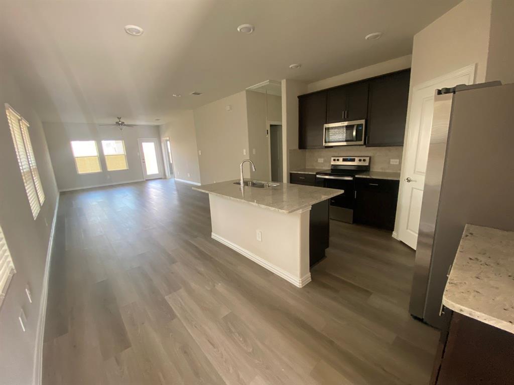 3220 Shortgrass Lane Melissa, TX 75454 - Photo 6 of 17 a kitchen with stainless steel appliances granite countertop a refrigerator a stove top oven a sink dishwasher and wooden floor