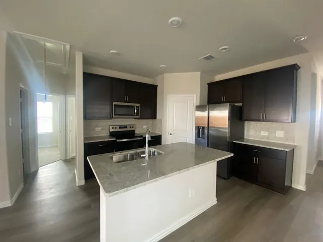 a kitchen with stainless steel appliances granite countertop a sink a stove and a refrigerator