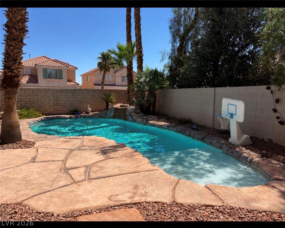 7815 Windward Road Las Vegas, NV 89147 - Photo 10 of 13 Textured flagstone decking surrounds an inviting private pool bordered by privacy fencing and palm trees.