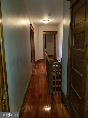 a view of a hallway with wooden floor and a bathroom