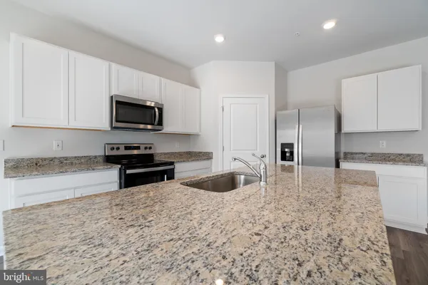 a kitchen with stainless steel appliances granite countertop a sink a stove and a refrigerator