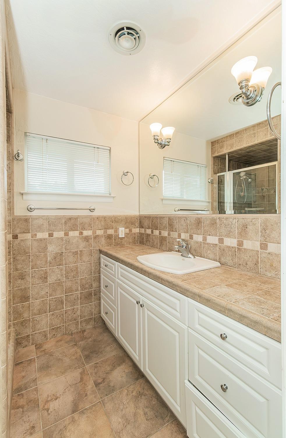 5662 North McCall Avenue Clovis, CA 93619 - Photo 14 of 34 a bathroom with a granite countertop sink a large mirror and a