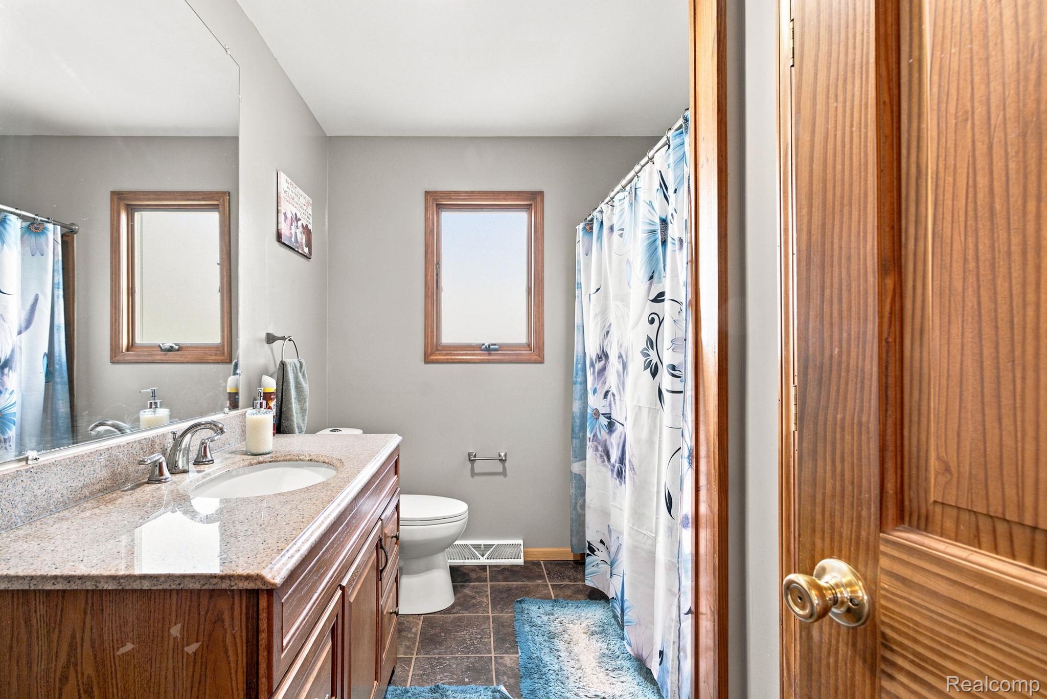 4201 Galbraith Line Road Croswell, MI 48422 - Photo 19 of 39 Bathroom featuring a vanity with a light granite-finish countertop, undermount sink, and chrome faucet