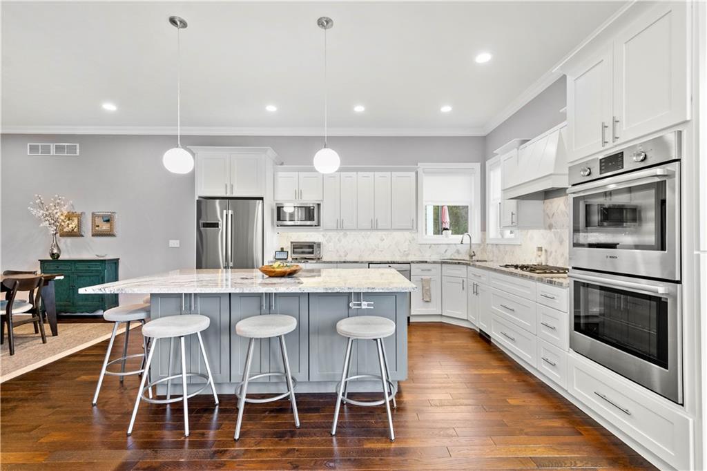 225 Meridan Street Pittsburgh, PA 15211 - Photo 7 of 25 a kitchen with stainless steel appliances granite countertop a stove top oven a sink dishwasher a dining table and chairs with wooden floor
