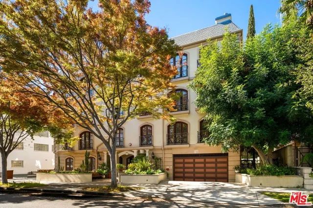 a view of a white house with large tree and wooden fence