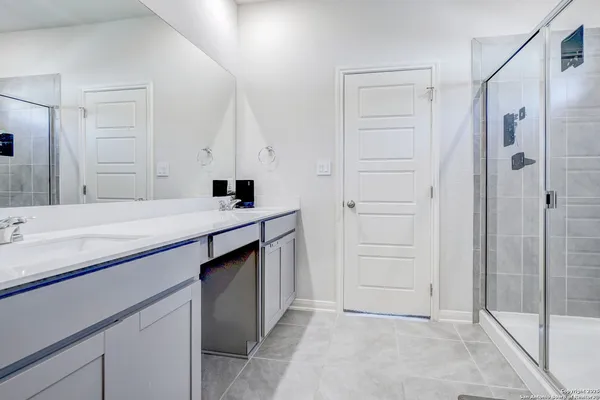 a bathroom with a double vanity sink a mirror and a shower