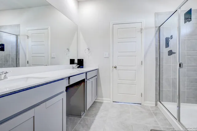 a bathroom with a double vanity sink a mirror and a shower