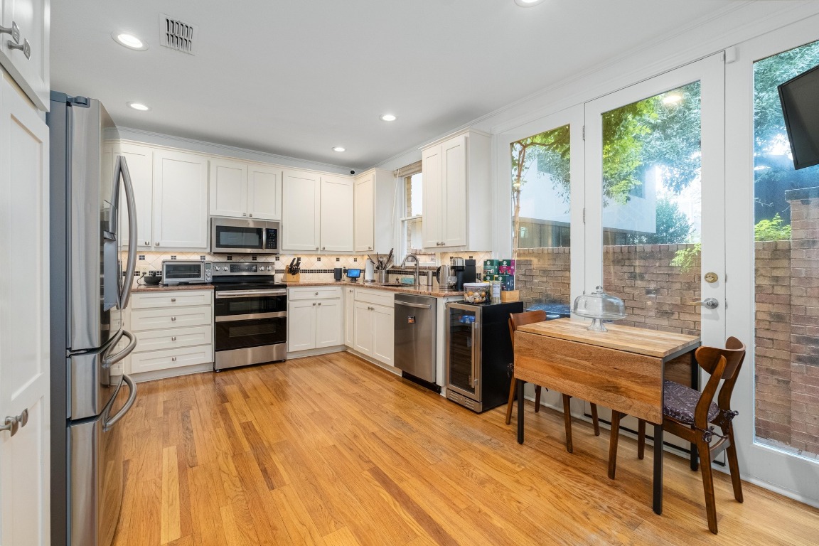 902 West 18th Street, Unit B Austin, TX 78701 - Photo 14 of 39 Kitchen featuring stainless steel appliances, white cabinetry, light wood-type flooring, granite countertops, and recessed lighting