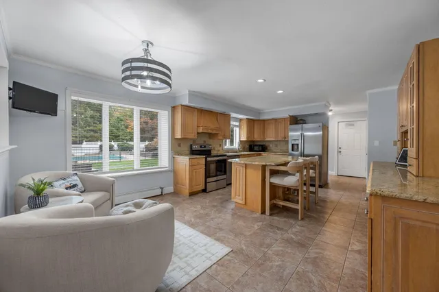 a living room with furniture kitchen area and a window