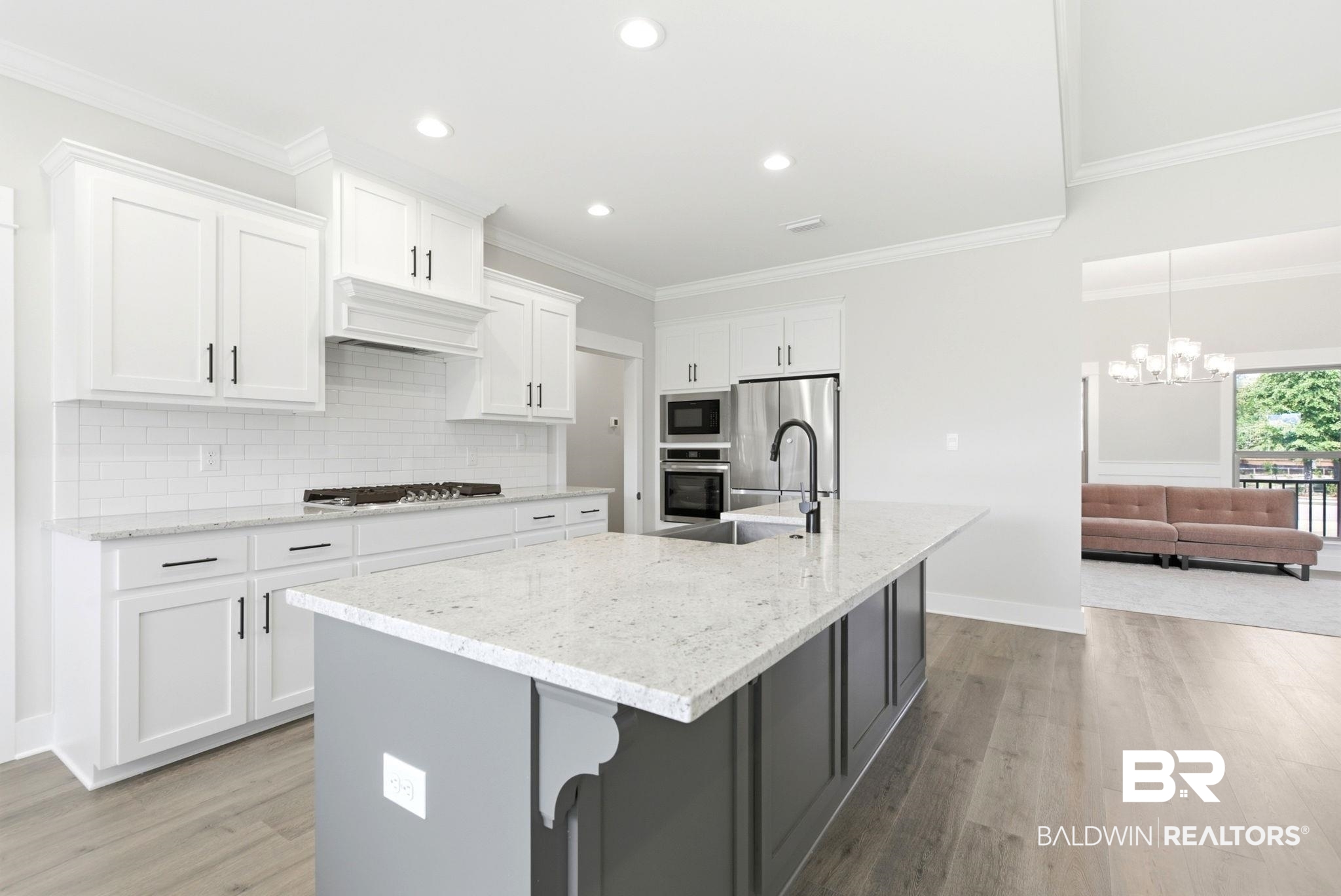 12132 Exbury Way Daphne, AL 36527 - Photo 10 of 47 Kitchen with light stone counters, a kitchen island with sink, tasteful backsplash, light wood-style flooring, and crown molding