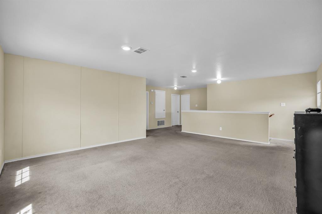 5718 Green Ivy Road Denton, TX 76210 - Photo 23 of 37 Spacious carpeted room featuring recessed lighting, light beige wall finishes, a half-wall partition with a wood handrail, and white trim throughout