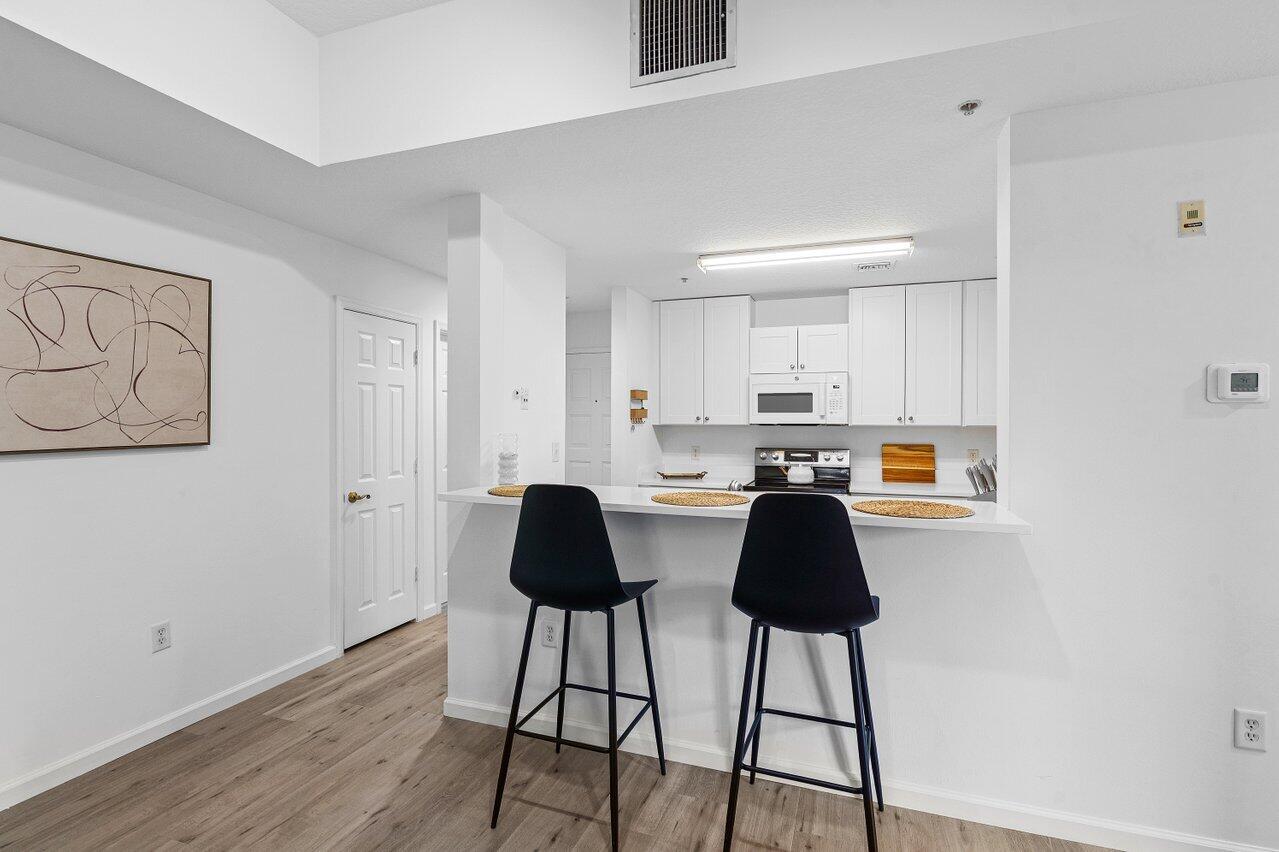 1209 Main Street, Unit 302 Jupiter, FL 33458 - Photo 3 of 35 a kitchen with a table chairs and wooden floor